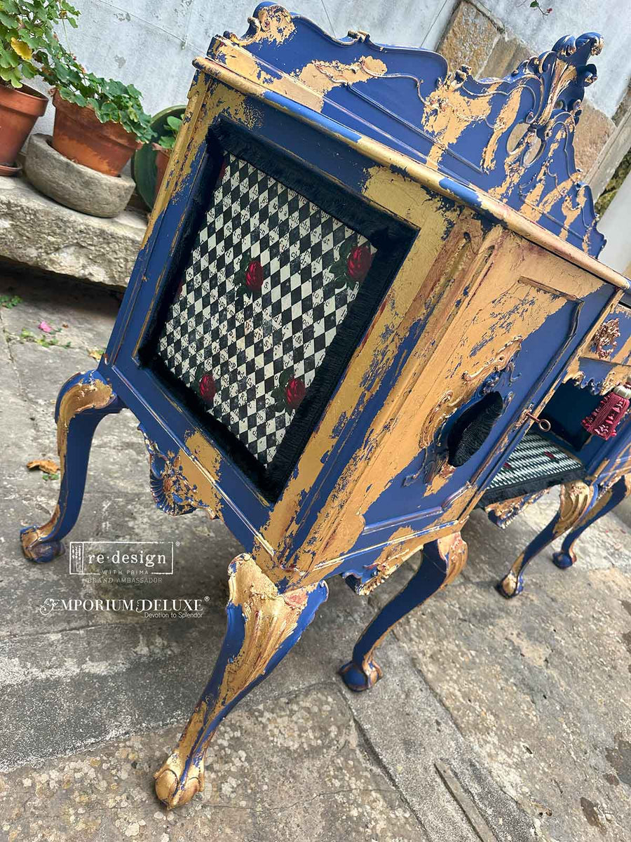 Baroque-style gold and blue nightstand with framed panel of Queen’s Court of Roses tissue, styled with distressed gilded finish.
