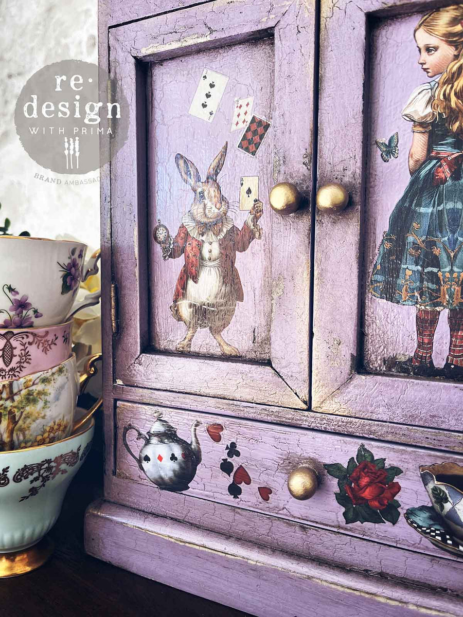Detail view of white rabbit and Alice transfers on a crackled lavender cabinet – embellished with floral and tea-themed elements.